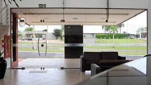 Um saguão de hotel com recepção, área de estar e vista para a rua.