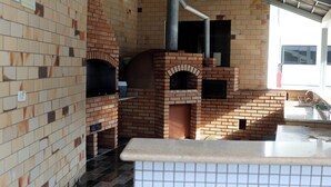 Forno de tijolos com bancada azulejada e pia.