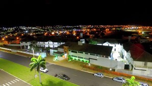 Hotel com design moderno, estacionamento e vista da paisagem urbana noturna.