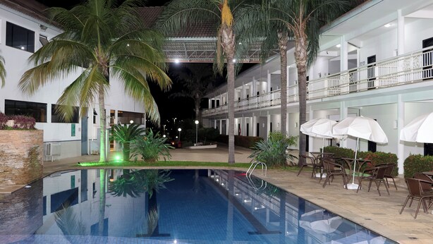 Piscina interna com vista desobstruída, cercada por palmeiras e área de estar ao ar livre.