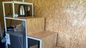 Eine kompakte Küche mit Kühlschrank, Wasserkocher und einer kleinen Regaleinheit.