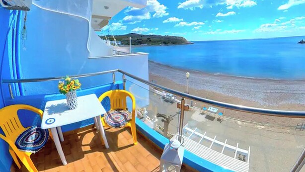 A balcony with a table, two chairs, and a vase of flowers. - Blue House Beach Apartment - Sleeps 4 & Balcony (Rhodes)