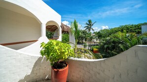 A white building with a brick wall and a potted plant. - Sueño - Playacar 2 Rosa Blanca - 2 BR (Playa del Carmen)