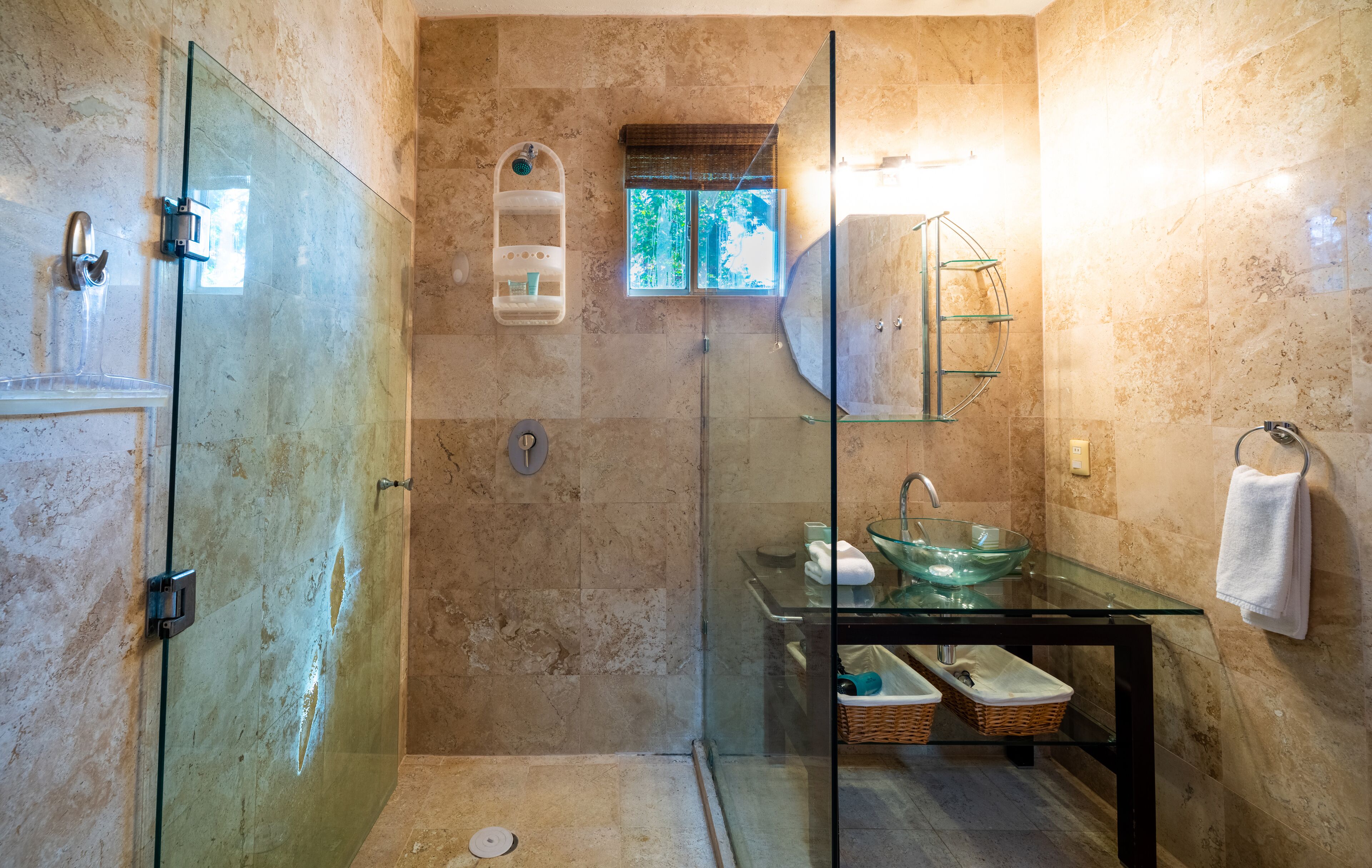 Une salle de bain moderne avec une douche à parois de verre, un lavabo en verre en forme de bol et une petite fenêtre.