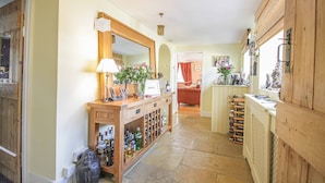 A hallway with a wooden cabinet, a mirror, and a small table with a lamp and flowers.