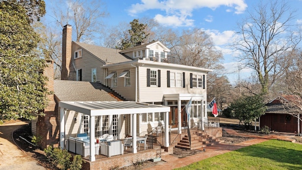 A two-story house with a covered porch, a chimney, and a flag.