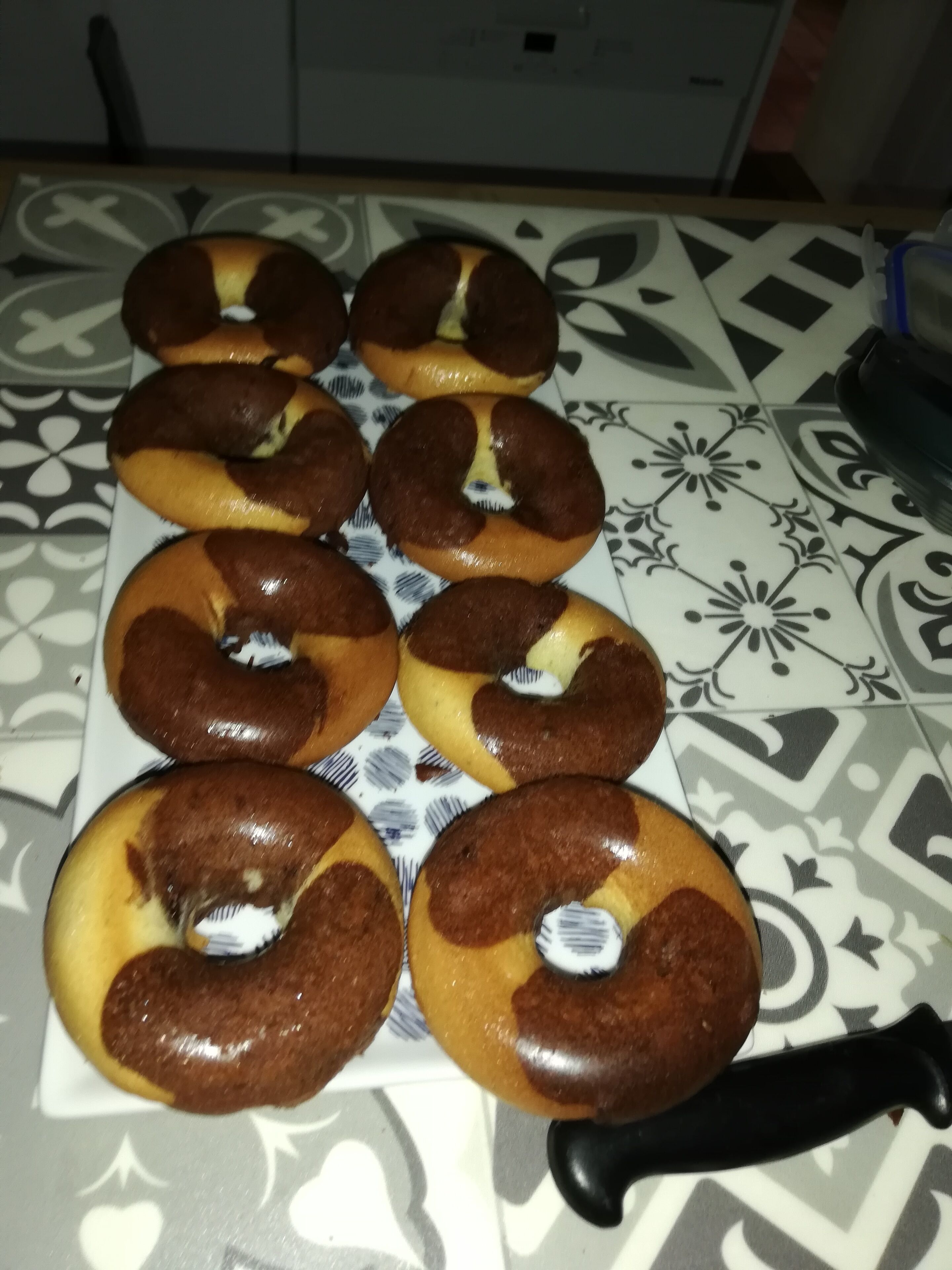 En bricka med bagels på ett mönstrat bordsduksunderlägg.