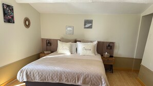 Une chambre avec un grand lit, deux tables de chevet, une lampe fixée au mur et un tapis.