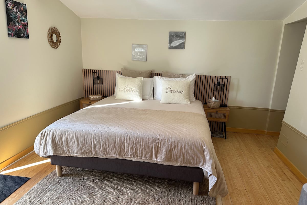 Ein Schlafzimmer mit einem großen Bett, zwei Nachttischen, einer Wandlampe und einem Teppich.