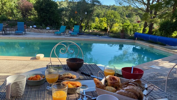 Une table dressée avec des aliments pour le petit-déjeuner, donnant sur une piscine.