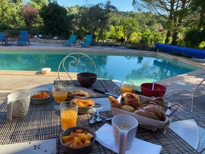 Ein Tisch mit Frühstücksangeboten und Blick auf ein Schwimmbad.