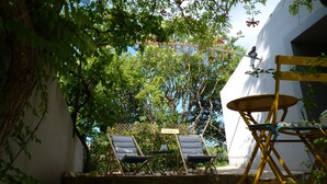Un espace patio comprenant deux chaises longues, une petite table et une chaise pliante jaune.