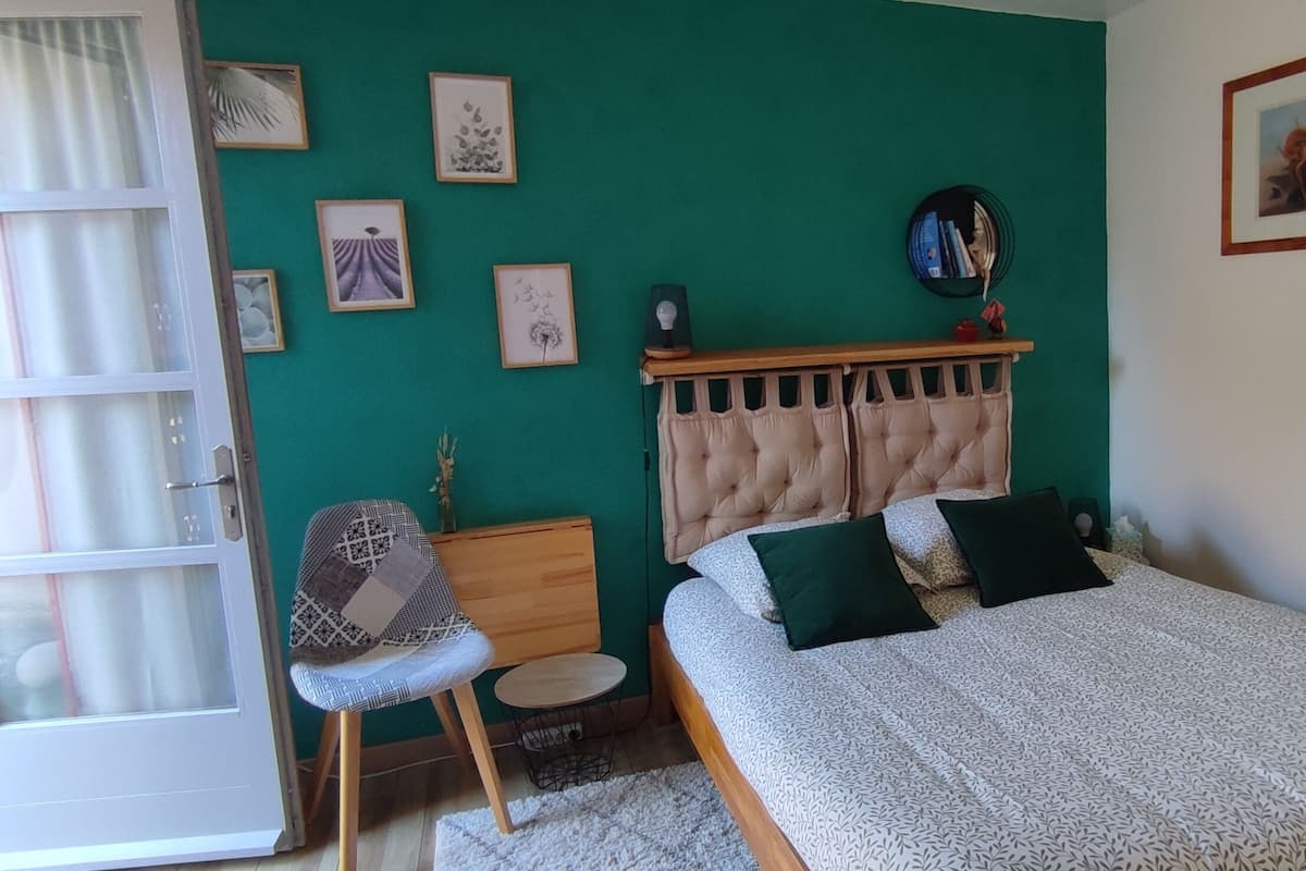 Ein Schlafzimmer mit Bett, Stuhl, einem kleinen Tisch und einem Fenster.