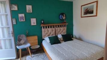 Un dormitorio con una cama, una silla, una mesita y una ventana.