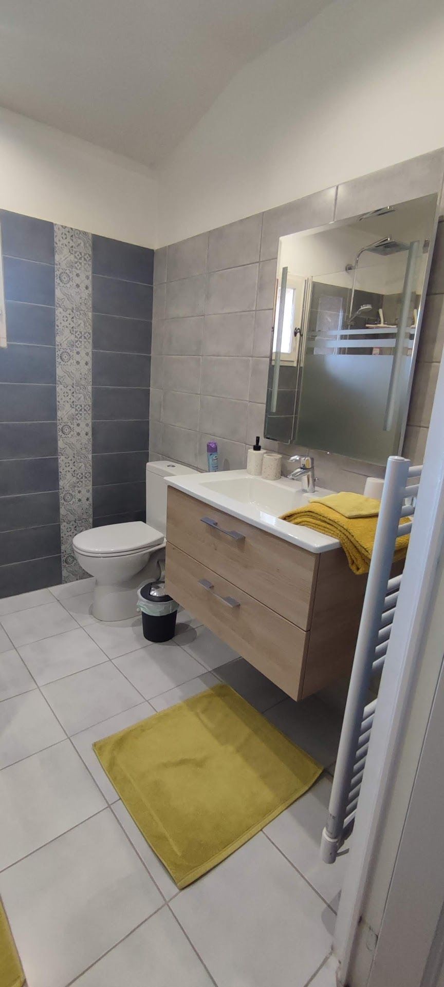 A modern bathroom with a toilet, sink, and mirror.