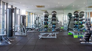 A modern gym with various exercise equipment, large mirrors, and ample natural light. - City Suite - Rooftop Spa - Balcony - Skyline View (Manchester)