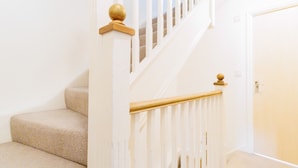 A staircase with beige carpeted steps and white railings with wooden balusters. - Orchid House in Cambridge (Cambridge)