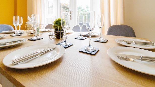 A dining table set with plates, cutlery, and wine glasses, with a small plant centerpiece. - Orchid House in Cambridge (Cambridge)
