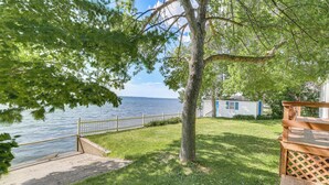 A lakeside property with a wooden deck, a fenced pathway, and a view of the water.