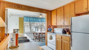 A kitchen with wooden cabinets, a stove, a refrigerator, and a dining table with chairs.
