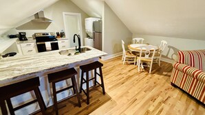 Une cuisine compacte avec un îlot central, une table à manger en bois et un canapé à rayures.