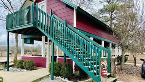 Une maison à deux étages avec un escalier vert menant à un porche.