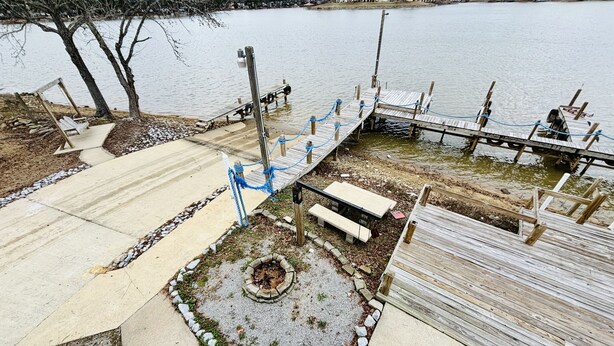 Une jetée en bois s’avançant dans un lac, avec une table de pique-nique et un espace aménagé pour faire un feu de camp.