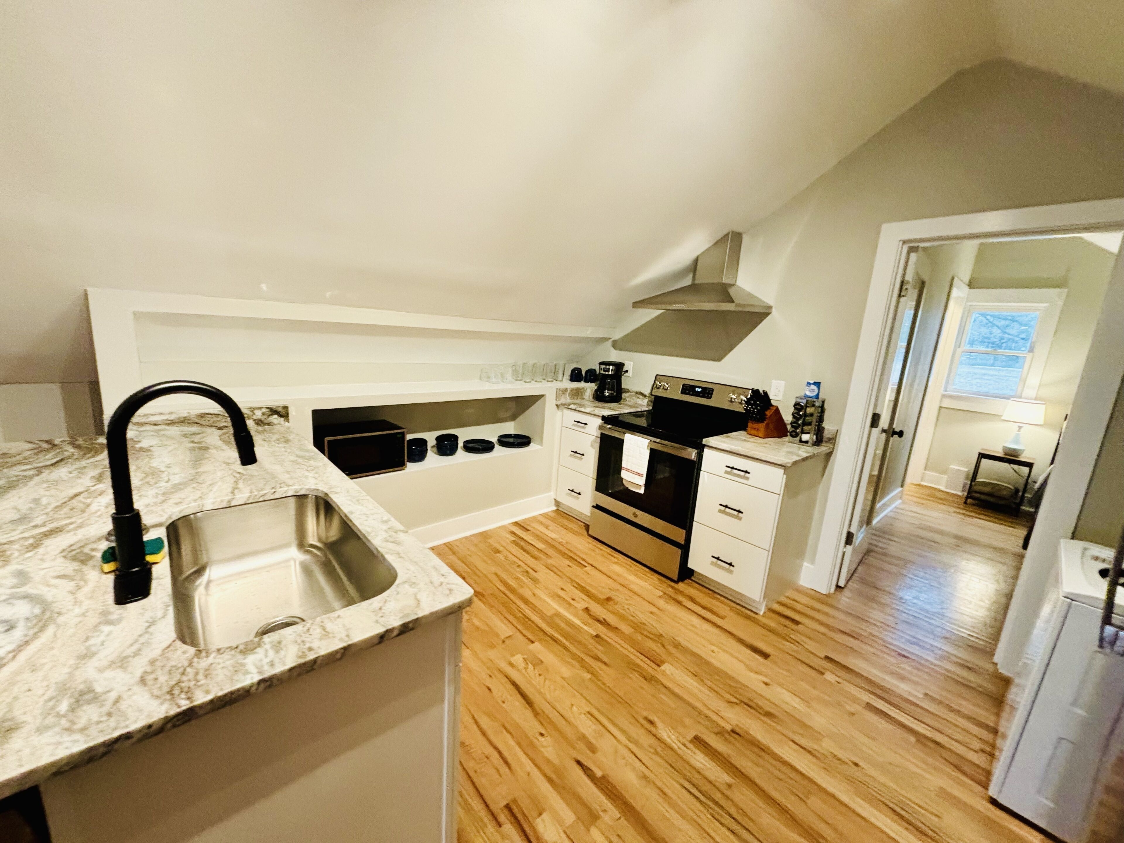 A compact kitchen with a sink, stove, and microwave.