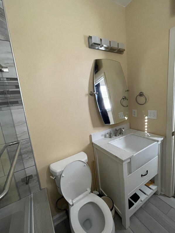 A bathroom with a toilet, sink, mirror, and a towel ring.