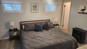 Un dormitorio con una cama grande, dos mesitas de noche con lámparas, un ventilador de techo y cuadros en las paredes.