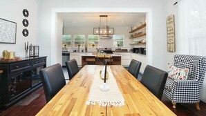 Una cocina moderna con comedor, que presenta una mesa de madera, sillas negras y una araña.