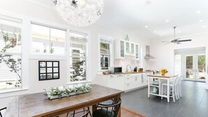 Eine moderne Küche mit weißen Schränken, einem Holztisch und einem Deckenventilator.