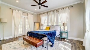Une chambre à coucher avec un lit, un banc, un ventilateur de plafond et une table de chevet.