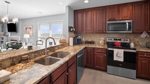 A modern kitchen with granite countertops, stainless steel appliances, and wooden cabinets. - Oceanview, Pet Friendly in Pelican Point (Saint Helena Island)