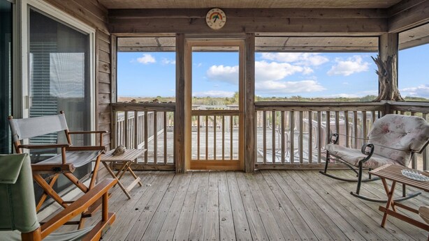 A wooden deck with a view of the beach, a wooden chair, a rocking chair, and a table. - Oceanview, Pet Friendly in Pelican Point (Saint Helena Island)