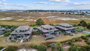 A coastal property with multiple buildings featuring elevated decks and staircases, surrounded by natural landscapes and a distant bridge. - Oceanview, Pet Friendly in Pelican Point (Saint Helena Island)