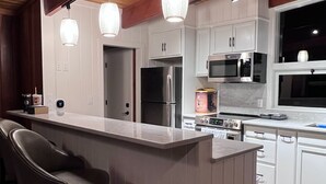 A modern kitchen with a central island, stainless steel appliances, and pendant lighting.