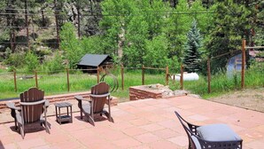 An outdoor patio with wooden and metal chairs, a bench, and a small table.
