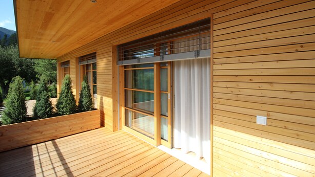Eine Holzausfachung mit großen Schiebegläsern und einer Terrasse.