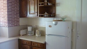 A compact kitchen with a refrigerator, a coffee maker, and wooden cabinets. - Maison de Campagne à 50 m de la Rivière Lot (Saint-Martin-Labouval)