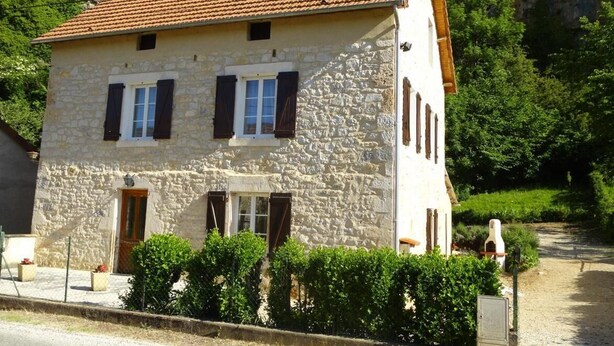 A stone building with a tiled roof, a small porch, and a door with a window. - Maison de Campagne à 50 m de la Rivière Lot (Saint-Martin-Labouval)