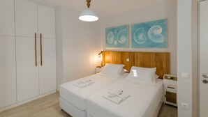 A double bed with white linens, a wooden headboard, and two bedside tables with lamps. There are two wall-mounted artwork pieces above the bed.