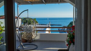A balcony with a hanging chair, potted plants, and a view of the sea.