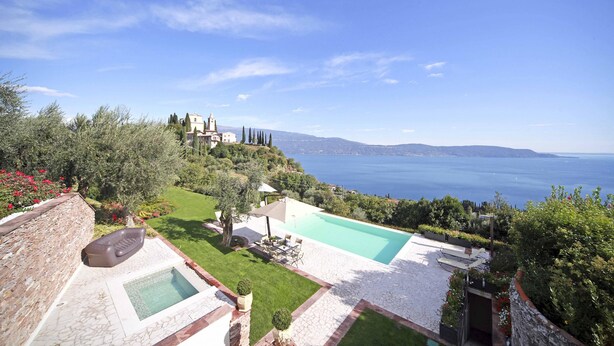 A pool area with a view of the sea, surrounded by greenery and a stone wall. - Villa Teodora in Toscolano-maderno (Toscolano Maderno)