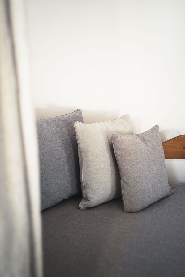 Un rincón de una habitación con un sofá gris y tres cojines.