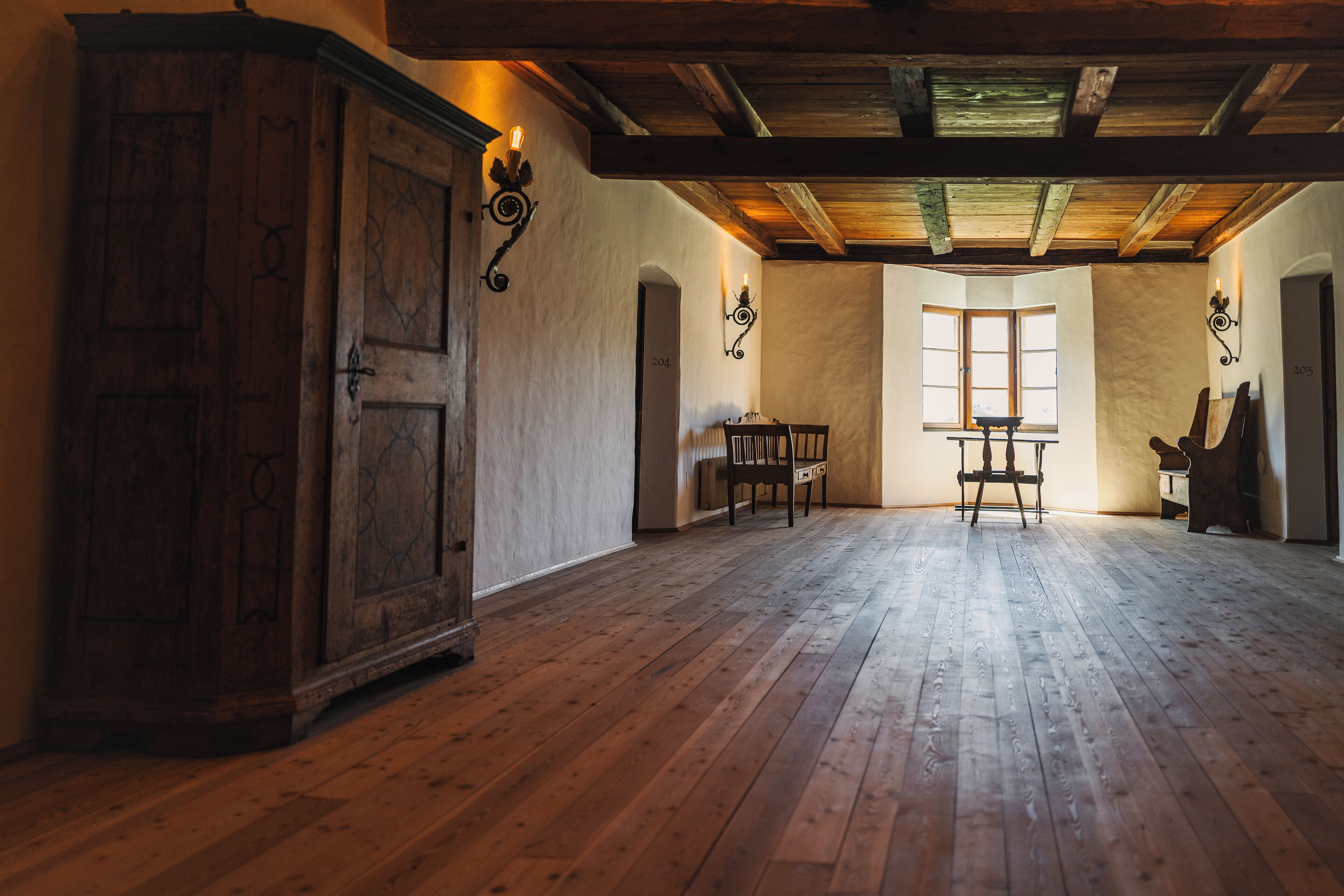 Una stanza spaziosa con pavimento in legno, un'ampia credenza in legno e un tavolo con sedie.