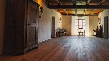 Una stanza spaziosa con pavimento in legno, un'ampia credenza in legno e un tavolo con sedie.