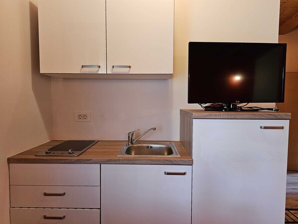 A compact kitchenette with a sink, cabinets, a countertop, and a flat-screen TV. - Studio Apartment FILIP (Rovinj)