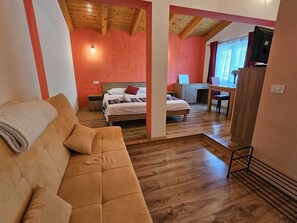 A cozy room with a wooden ceiling, a bed with a red pillow, a desk with a chair, and a TV on a stand. - Studio Apartment FILIP (Rovinj)