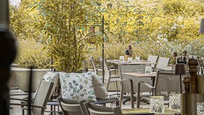 An outdoor dining area with tables and chairs, surrounded by greenery. - Best Western Hotel Spinnerei Linz (Linz)